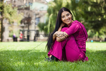 Happy young girl sitting on grass in park