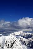 Winter snowy sunlit mountains and sky with clouds