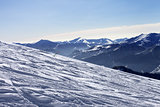 Ski slope with trace of ski, snowboards and mountains in haze