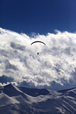 Winter mountains with clouds and silhouette of parachutist