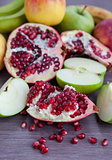 Fresh pomegranate and apples on a wooden table