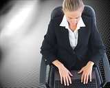 Blonde businesswoman sitting on swivel chair with laptop