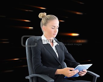 Blonde businesswoman sitting on swivel chair with tablet