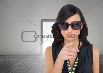 Elegant brunette wearing sunglasses pointing at camera