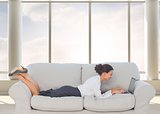 Businesswoman lying on couch using laptop