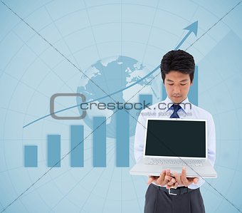 Businessman showing a laptop in front of statistic