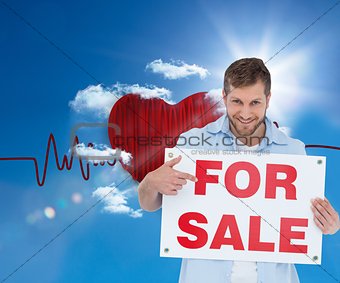 Smiling model holding a for sale sign