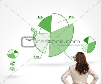 Businesswoman standing back to camera watching green diagrams