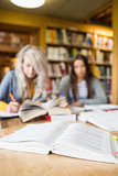 Two blurred students writing notes at library desk