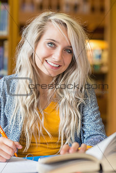 Smiling female student sitting at library desk