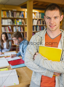 Male student with others in background at library