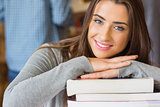 Smiling female student with stack of books at library