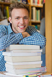 Male student with stack of books at library