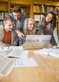 Students using laptop at desk in library
