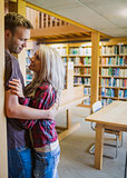 Young romantic couple with bookshelf at distance in library
