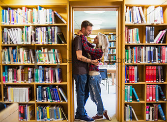 Romantic couple embracing by bookshelves in library