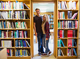 Young couple by bookshelves in the library