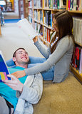Romantic couple with books at the library aisle
