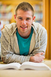 Male student with book on the college library floor