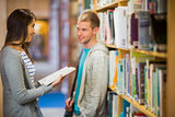 Couple standing against bookshelf in library