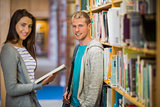 Students standing by bookshelf in the library