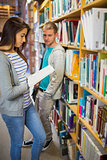 Two students by bookhelf in the library