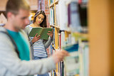 Students by bookshelf in the library