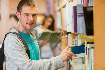 Student selecting a book from bookshelf in the library