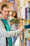 Student selecting a book from bookshelf in the library