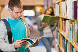 Students reading by bookshelf in the library