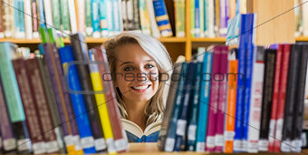 Smiling female student reading book in the library