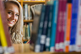 Smiling female amid bookshelves in the college library