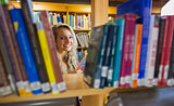 Smiling female amid bookshelves in the library