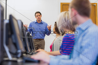 Teacher explaining to students in computer room