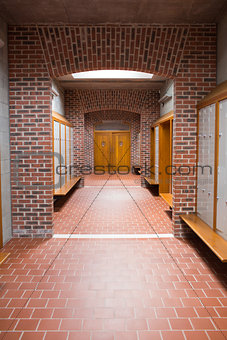 Empty brick walled corridor with tiled flooring in college