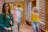 Smiling girl with blurred students walking through corridor