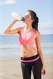 Beautiful healthy woman drinking water on beach