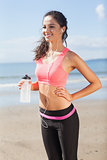 Beautiful smiling healthy woman holding water bottle on beach