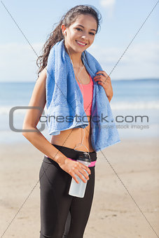Beautiful smiling healthy woman with water bottle on beach
