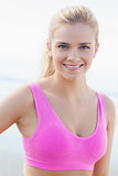 Smiling healthy woman in pink sports bra on beach