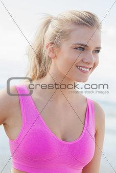 Smiling healthy woman in pink sports bra on beach