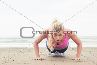 Beautiful woman doing push ups on beach