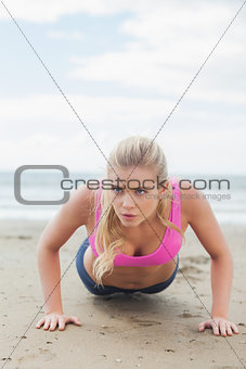 Beautiful woman doing push ups on beach