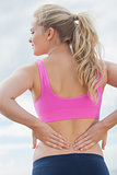 Rear view of healthy woman suffering from back pain on beach
