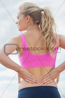 Rear view of healthy woman suffering from back pain on beach