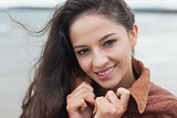 Cute smiling woman in stylish brown jacket on beach