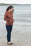 Cute young woman in stylish brown jacket on beach