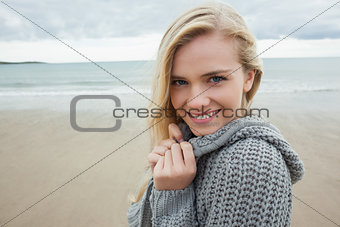 Cute smiling young woman in gray knitted jacket on beach