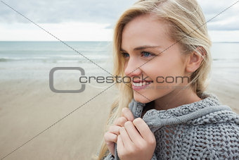Cute smiling woman in gray knitted jacket on beach