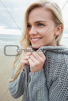Cute smiling woman in gray knitted jacket on beach